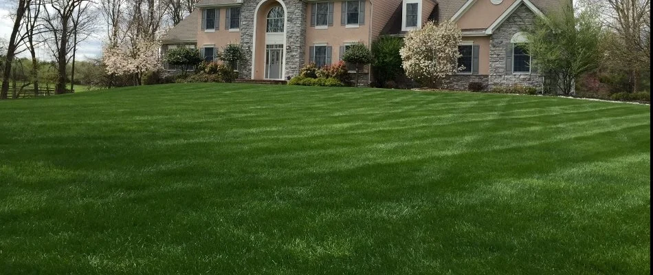 A house with a lush, green front lawn with surrounding landscape.