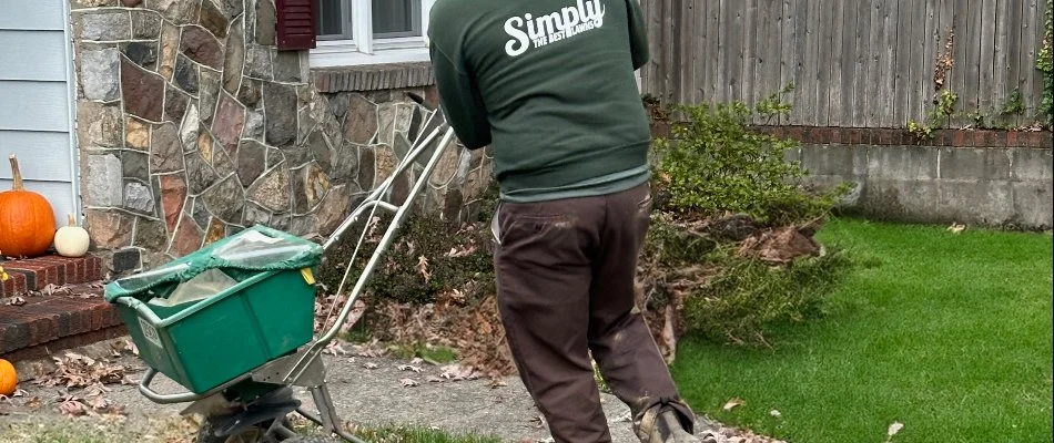 Tech pushing a granular spreader on grass in Fair Lawn, NJ.
